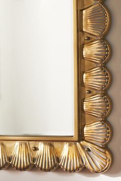 a gold framed mirror with scallops on the edges