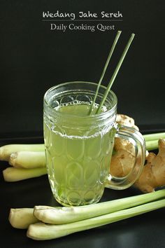 a glass mug filled with liquid next to celery stalks and ginger root stems