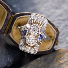 an antique diamond and sapphire ring sits on top of a rock in the sun light