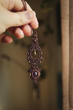 a hand holding a brown beaded necklace with pearls and beads hanging from it's end