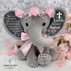 an elephant with pink flowers and pearls on its head sitting next to some pink flowers