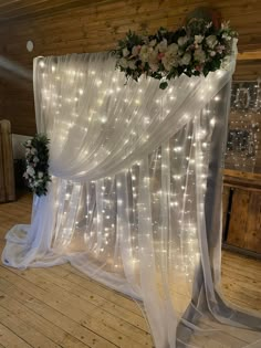 a white wedding arch decorated with flowers and lights