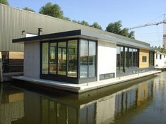 a houseboat is floating on the water in front of a building with glass windows