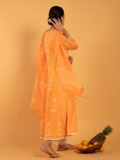 Set of 3 consists of kurta, pants, and dupatta. A summer bright orange kurta enriched with white khari print set on a light cotton base Kurta: Kalidar kurta with white khari print flowers, 3/4th sleeves and contrast white lace detailing on hemline, neckline and sleeves Dupatta: Handspun kota doria dupatta in orange and white, adorned with tassels and khari print Pants: Narrow ivory cotton pants with scallop lace edging. Fit: Relaxed & straight fit Wash Care Instructions: Dry Clean Only Note: Kalidaar Kurta, Kurta Pants, Print Pants, Kurta Set, Scalloped Lace, Lace Edging, Printed Pants, Cotton Pants, Cotton Lights