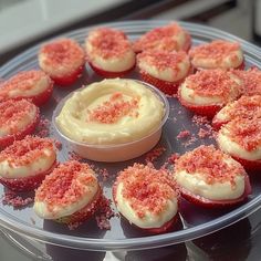 cupcakes with white frosting and red sprinkles are arranged in a circle