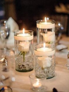 two clear vases filled with white flowers and candles