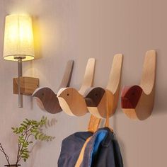 three wooden birds hang on the wall next to a coat rack with a blue jacket hanging from it