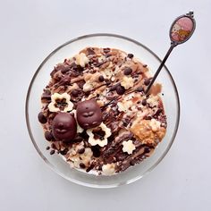 a bowl filled with chocolate and nuts on top of a white table next to a spoon