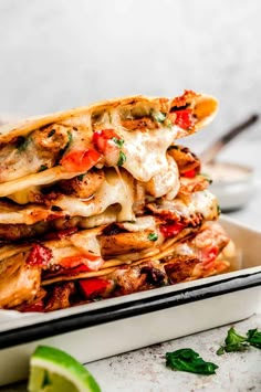 a stack of quesadillas on a plate with lime wedges next to it