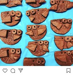 twelve carved wooden owls sitting on top of a blue surface