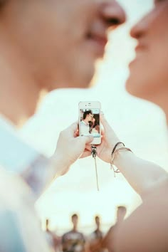 a man and woman are taking pictures with their cell phones while standing close to each other