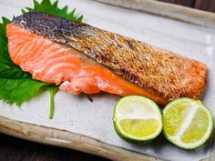 a piece of salmon on a plate with limes