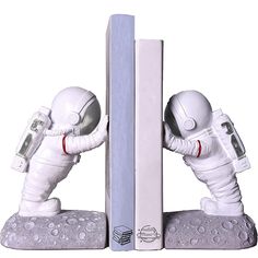 an astronaut figurine is posed next to a bookender with the cover open