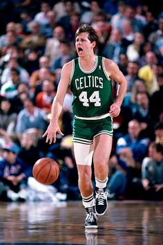 a basketball player dribbling the ball during a game with an audience in the background