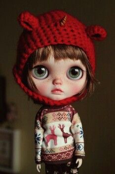 the doll is wearing a red hat and sweater