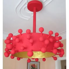 a red and gold chandelier with balls hanging from it's center piece