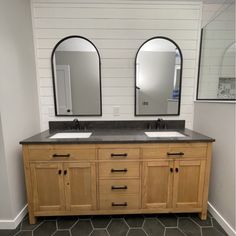 a bathroom with double sinks and two mirrors on the wall next to eachother