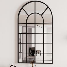 an arched mirror hangs on the wall above a sink