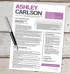 a purple and white resume on top of a wooden table with a pen next to it