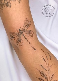 a woman's arm with a dragonfly tattoo on it