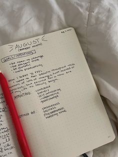 an open notebook with writing on it and a red pen