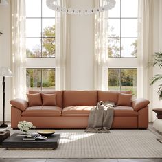 a living room filled with lots of windows next to a couch and coffee table on top of a rug