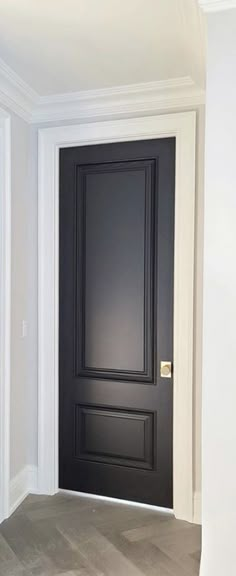 an empty room with a black door and white trim on the walls is seen in this image