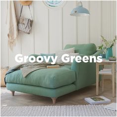 a green couch sitting on top of a wooden floor next to a table and lamp