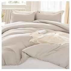 an unmade bed with white sheets and pillows