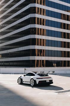 a white sports car parked in front of a tall building