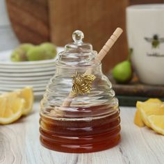 a honey jar filled with liquid sitting on top of a table next to sliced lemons