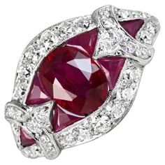 This exquisite gemstone ring showcases a captivating 1.08 carat oval cut natural ruby at its center. Flanking the ruby are French cut rubies, meticulously arranged to create a striking geometric design, enhancing the vibrancy of the center stone. Surrounding the ruby is a halo of sparkling old European cut diamonds, further elevating the ring's brilliance. Each shoulder of the band is adorned with a single French cut ruby, complemented by additional old European cut diamonds, with a total diamon Heirloom Oval Gia Certified Ruby Ring, Oval Ruby Diamond Ring, Oval Ruby Ring With Platinum Band, Oval Ruby Ring With Platinum Setting, Heirloom Oval Ruby Ring Gia Certified, Red Oval Diamond Cut Diamond Ring, Red Oval Diamond Cut Ring, Red Oval Diamond Ring With Diamond Cut, Art Deco Oval Ruby Ring For Anniversary