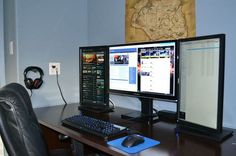 two computer monitors sitting on top of a desk next to a keyboard and headphones