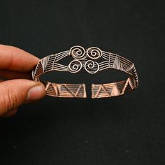 a person is holding a bracelet with designs on it