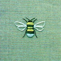 a close up of a bee on a green cloth with yellow and black stripes in the center