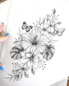 a woman's hand holding a pen and drawing flowers on paper with butterflies in the background