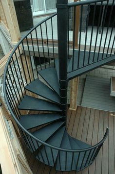 a black spiral staircase on a wooden deck