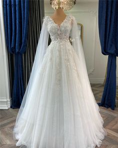 a white wedding dress on display in front of a mirror with blue curtains behind it