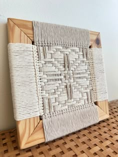 an art piece made out of woven material on a wooden frame, sitting on top of a wicker floor