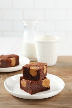 three pieces of brownie with peanut butter on top are sitting on a white plate