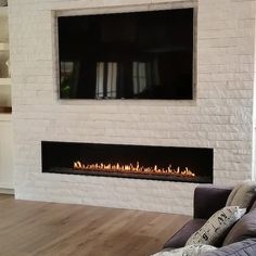 a living room with a couch, fireplace and flat screen tv mounted on the wall