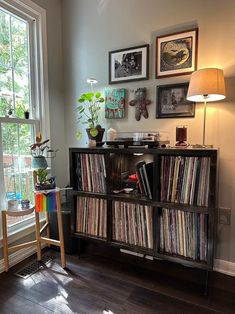 an old record player sits in front of a window with pictures on the wall behind it