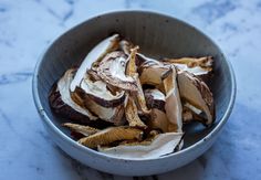 a bowl filled with sliced bananas on top of a table next to a marble counter