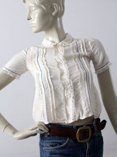 "This is a vintage silk blouse circa 1920s. The cream silk top features pin tuck pleats down the front with blue laced stitching and lace trim. It buttons closed. CONDITION In great condition. Approximate Fit: XS MEASUREMENTS Bust: 30\" ... 76.2 cm Length: 18\" ... 45.7 cm Shoulders: 12\" .. 30.5 cm Outside Sleeve: 8\" ... 20.3 cm HOW WE MEASURE * Blouse measured lying flat * Bust measured armpit to armpit * Length measured down the center of the back * Shoulders measured between the shoulder se Silk Tops With Lace Trim For Daywear, Victorian Cotton Fitted Blouse, Fitted Victorian Cotton Blouse, Cream Top With Ruffled Collar For Daywear, Short Sleeve Tops With Pintucks For Daywear, Vintage Lace Collar Button-up Top, Vintage Cream Blouse With Ruffles, Victorian Fitted Tops For Summer, Fitted Victorian Summer Tops