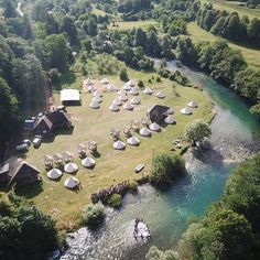 an aerial view of several tents in the middle of a field next to a river