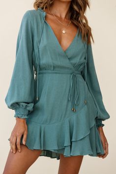 Turn heads in our ultra chic Santorini dress. Partially lined, it features long sleeves with elasticated cuffs, surplice neckline, string tie around the waist and a ruffle hem. Wear it to work teamed with flats and a tote or dress it up with heels... Santorini Dress, Cowboy Chic, Dress Sage, Yellow Bridesmaids, Red Bridesmaids, Blue Bridesmaids, Clothing Tags, Date Night Dresses, Mini Dress Casual