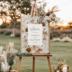 an easel decorated with flowers and greenery for a welcome sign to the couple