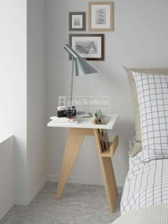 a bed room with a neatly made bed next to a desk and pictures on the wall