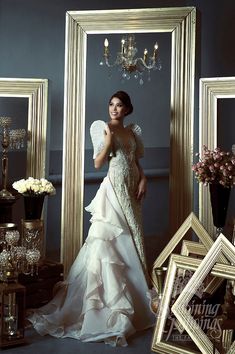 a woman standing in front of a mirror wearing a wedding dress with ruffles