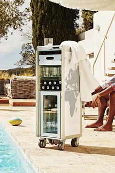 a wine cooler sitting next to a pool with people sitting on the side of it